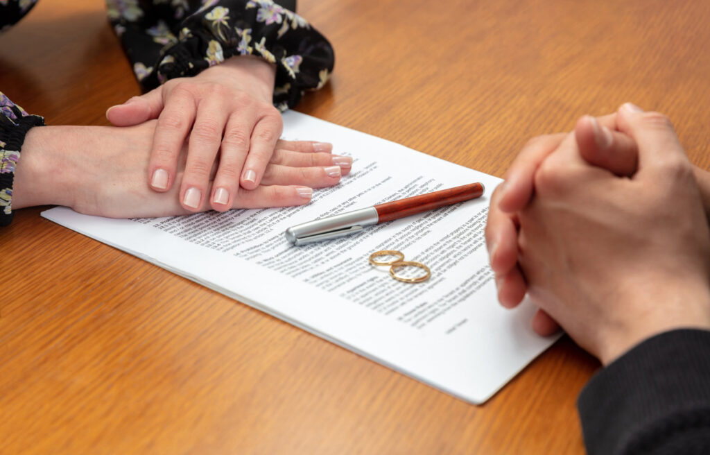 Divorce agreement document with wedding ring and signature at lawyer’s office table